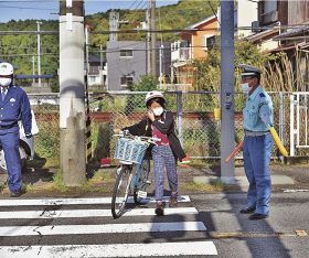 自転車で通学する児童（中央）に交差点の渡り方を指導する交通指導員（右）＝白浜町堅田で