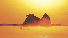 朝日に照らされて黄金色になった海霧の中を進む漁船（１６日午前７時１０分、和歌山県串本町田原で）