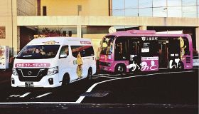 町内を中心に運行する白色のミニバスとピンク色の中型バス（上富田町朝来で）