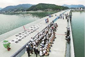 熊野川河口大橋で開かれた体験学習会に参加し、県境で記念撮影をする子どもら（２６日、和歌山県新宮市で）
