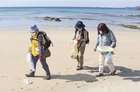 芝﨑浩子さん（左）の案内で須賀の浜で貝殻などの漂着物を拾う参加者＝和歌山県串本町串本で