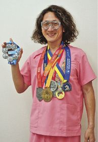 世界六大マラソン大会のメダルを掛け、シックススターフィニッシャーのメダルを持つ佐藤昌昭さん
