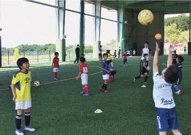 サッカーボールを真上に投げる運動をする小学生（上富田スポーツセンターで）