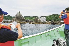 漁船からロケットの打ち上げを見学する取り組みの試運航で、海側から橋杭岩を見る参加者（和歌山県串本町くじの川沖で）