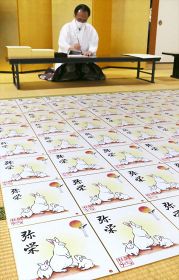 来年のえと「卯」を描いた色紙と男成洋三宮司＝１８日、那智勝浦町の熊野那智大社で