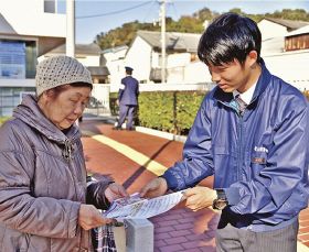銀行の利用者（左）に啓発品を手渡す白浜署員＝１６日、和歌山県白浜町で