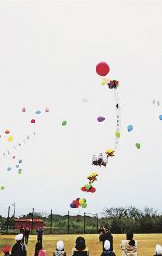 空に向かって風船を飛ばす児童（３日、和歌山県串本町潮岬で）