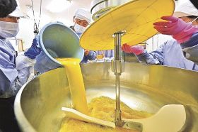 ポンカンから搾った果汁を加熱殺菌するための機械に入れる作業（和歌山県串本町伊串で）