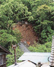 斜面の崩落で谷崖に落ちた須佐神社の社務所。屋根だけが見えている（７日、和歌山県田辺市中辺路町西谷で）