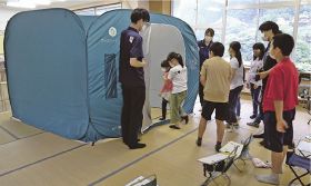 田辺市防災まちづくり課の職員が持参した市の折り畳み式テントを見学する児童
