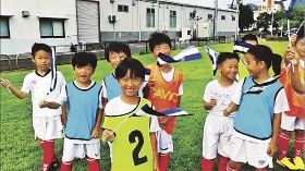 上富田フットボールクラブが制作した応援動画で、笑顔でホンジュラス国旗を振る子どもたち＝関係者提供