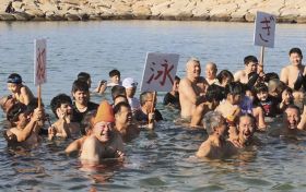 海水の冷たさに悲鳴を上げる参加者（和歌山県田辺市の扇ケ浜海水浴場で）