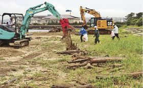 砂浜に打ち上げられた流木などを撤去する人見建設の社員ら（９日、和歌山県串本町くじの川で）