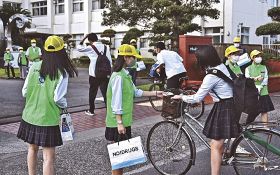 登校してきた生徒に啓発品を配る生徒会の役員ら（１３日、串本町串本で）