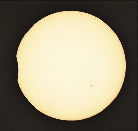 左側が欠けた太陽（２０日午後２時３８分、和歌山県串本町潮岬から）＝日食観察用のアクリル板を使って撮影