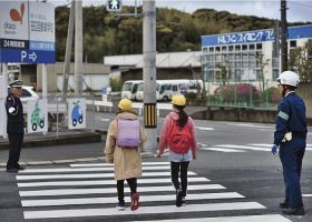 通学する児童を見守る交通指導員（左）と田辺署員＝１３日、和歌山県田辺市新庄町で