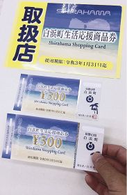 和歌山県白浜町が町民に配布する商品券（下）。使える事業所は「取扱店」のシール（上）を張っている