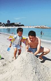 砂浜で遊ぶ親子（３１日、和歌山県白浜町の白良浜で）
