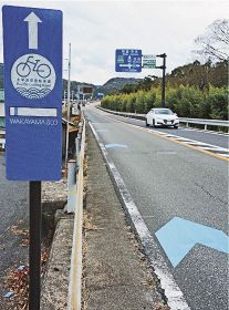 自転車道のルートを示す案内板と矢羽根形の道路標示（和歌山県白浜町十九渕で）
