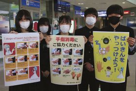 手指の消毒を呼び掛けるポスターを持つ富田中学校の生徒たち（和歌山県白浜町の南紀白浜空港で）