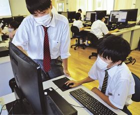 高校生（左）からプログラミングの基礎を教わる中学生＝和歌山県田辺市あけぼので