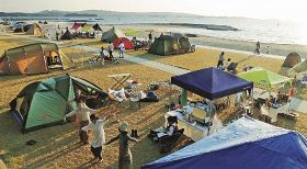 夕日を浴びてテントが並び、にぎわうキャンプイベント（和歌山県田辺市の扇ケ浜で）