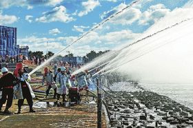 海に向かって一斉に放水する消防団員（５日、和歌山県の田辺市扇ケ浜で）