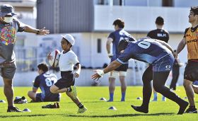 日野レッドドルフィンズの選手に捕まらないよう、ラグビーボールを持って走る西向小学校の児童（和歌山県串本町サンゴ台で）