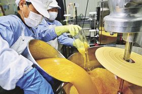 ポンカンから搾った果汁を加熱殺菌するための機械に入れる関係者（和歌山県串本町伊串で）