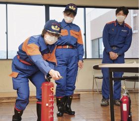 消防職員（右）に教わって消火器の使い方を練習する下野栄さん（左）と栗山和歌子さん＝和歌山県みなべ町徳蔵で
