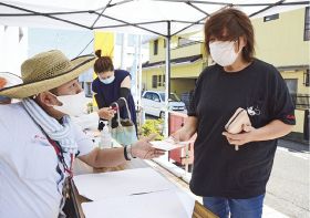 郵便局ではがきと商品券を引き換える手続きをする町民（右）＝１３日、和歌山県串本町串本で