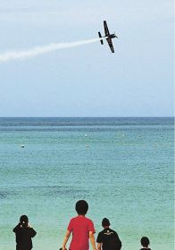 白良浜上空で曲技飛行を披露するプロペラ機（６日、和歌山県白浜町で）