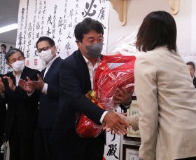 事務所スタッフ（右）から花束を受け取る鶴保庸介さん（10日午後８時ごろ、和歌山市の事務所で）