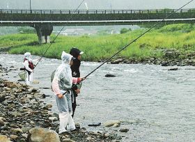 雨が降る中、釣り糸を日置川に垂らす参加者（１６日、和歌山県田辺市中辺路町近露で）