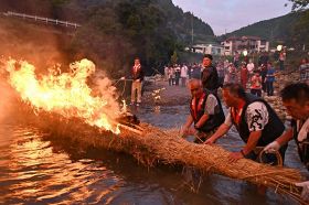 盆の伝統行事である「下川上の流れ施餓鬼」で、燃えさかるわら舟を下流へと流す関係者（和歌山県田辺市下川上で）
