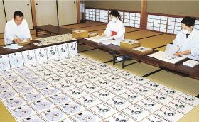 １枚ずつ色紙を仕上げていく熊野本宮大社の九鬼家隆宮司（左）ら＝１５日、和歌山県田辺市本宮町で
