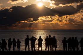 太平洋から昇った初日の出の太陽を見る若者たち（１日１日午前７時24分、新宮市の王子ヶ浜で）