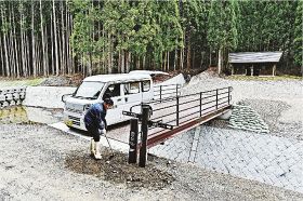 新たに架けた橋のたもとに、熊野古道の道標を設置する関係者（和歌山県田辺市本宮町三越で）
