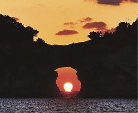 「だるま夕日」となって円月島の海食洞に沈む夕日（４日午後５時、和歌山県白浜町で）