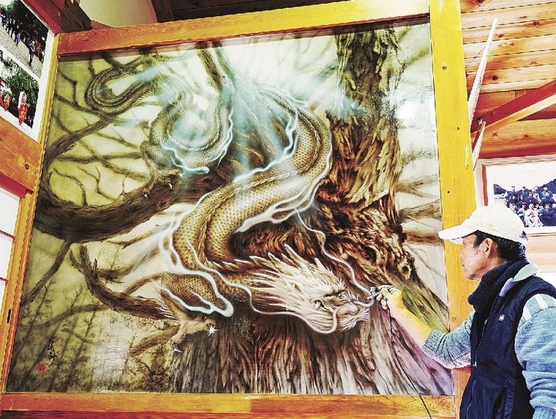 地元の巨木「龍神さん」と龍の絵をエアブラシで描いた柴田友助さん（和歌山県みなべ町清川で）