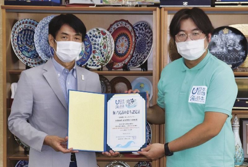 田嶋勝正町長（左）に認定書を手渡す沼田心之介さん＝２１日、和歌山県串本町串本で