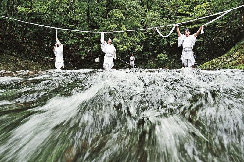 水量が多かったため、那智の滝の滝口の上流５０メートルほどの場所に大しめ縄を張る神職（１３日、和歌山県那智勝浦町で）