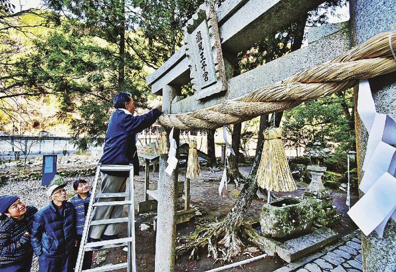 滝尻王子の鳥居に新しいしめ縄を飾る関係者（２８日、和歌山県田辺市中辺路町栗栖川で）