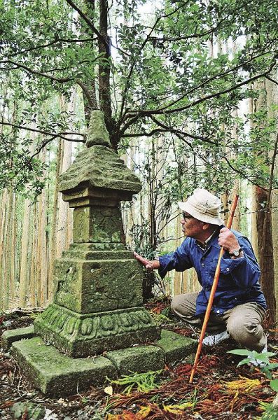 箸折峠で、花山法皇の経塚と伝わる石塔と、それを見つめる久保智彦さん（田辺市中辺路町近露で）