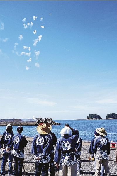 鹿島を背景に、打ち上がった奉納花火を見上げる鹿島神社総代（和歌山県みなべ町埴田で）