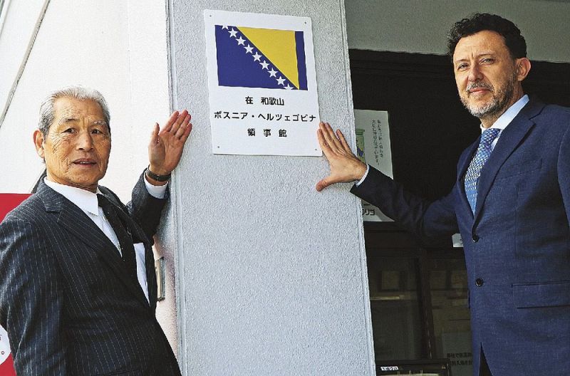 物流会社の玄関に名誉領事館の看板を掲げるズラタン・ブルジッチ外務省大臣官房長（右）と長井保夫名誉領事＝２３日、和歌山市で