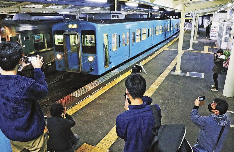 串本駅に到着した１０５系電車を写真に収める鉄道ファン（１２日、和歌山県串本町串本で）