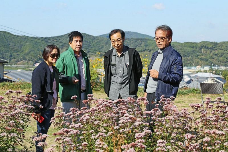 「アサギマダラの丘」の説明を聞く邱榮光さん（左から２人目）。右端はＤａｒｕｍａＣＬＵＢの吉田耕司代表。左隣は金澤至さん＝和歌山県上富田町市ノ瀬で