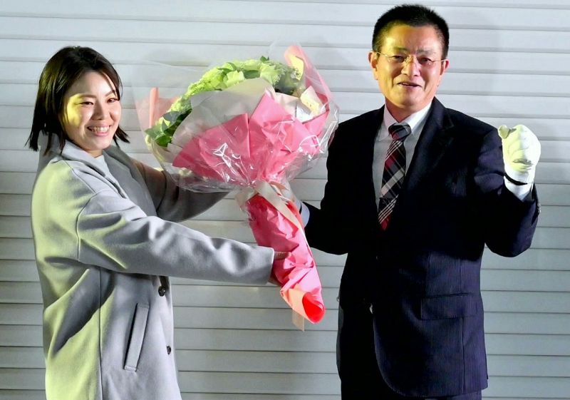 当選の花束を受ける奥田誠さん（右）＝30日午後９時20分、和歌山県上富田町で