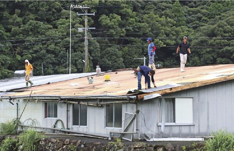 風で飛ばされた倉庫のトタン屋根を片付ける作業員（２７日、和歌山県串本町上田原で）